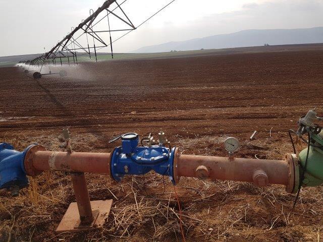 Blue irrigation flow meter installed on an agricultural water line in a field